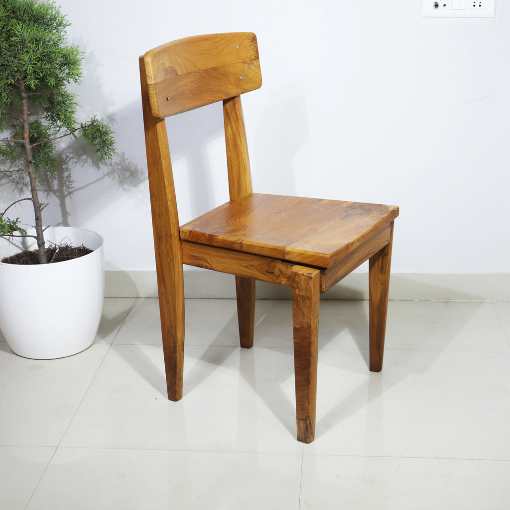 Wooden chair on a white floor with a plant in the background
