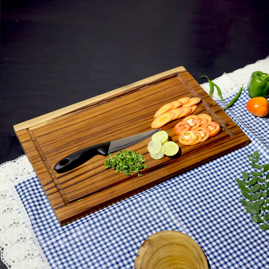 Wooden cutting board with knife and sliced vegetables on a checkered tablecloth