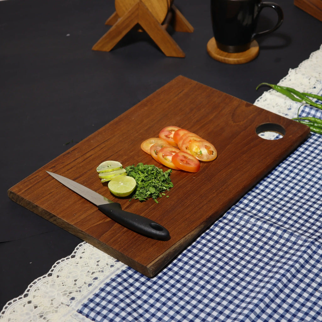 Wooden cutting board with sliced vegetables and a knife on a checkered tablecloth.