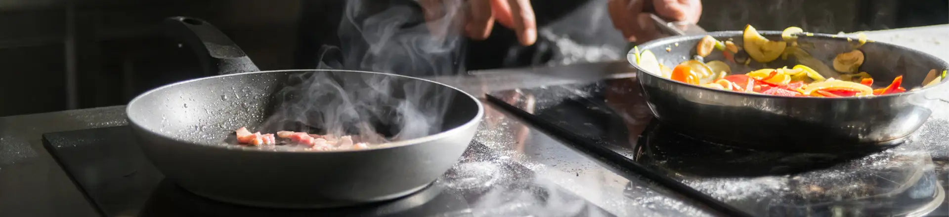 Two frying pans on a stovetop with food being cooked, one pan has steam rising from it.