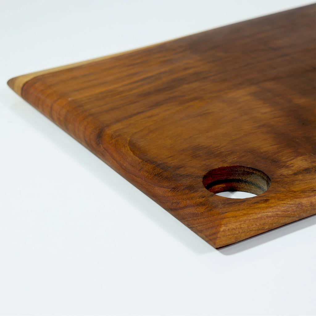 Wooden cutting board with a hole for hanging on a white background