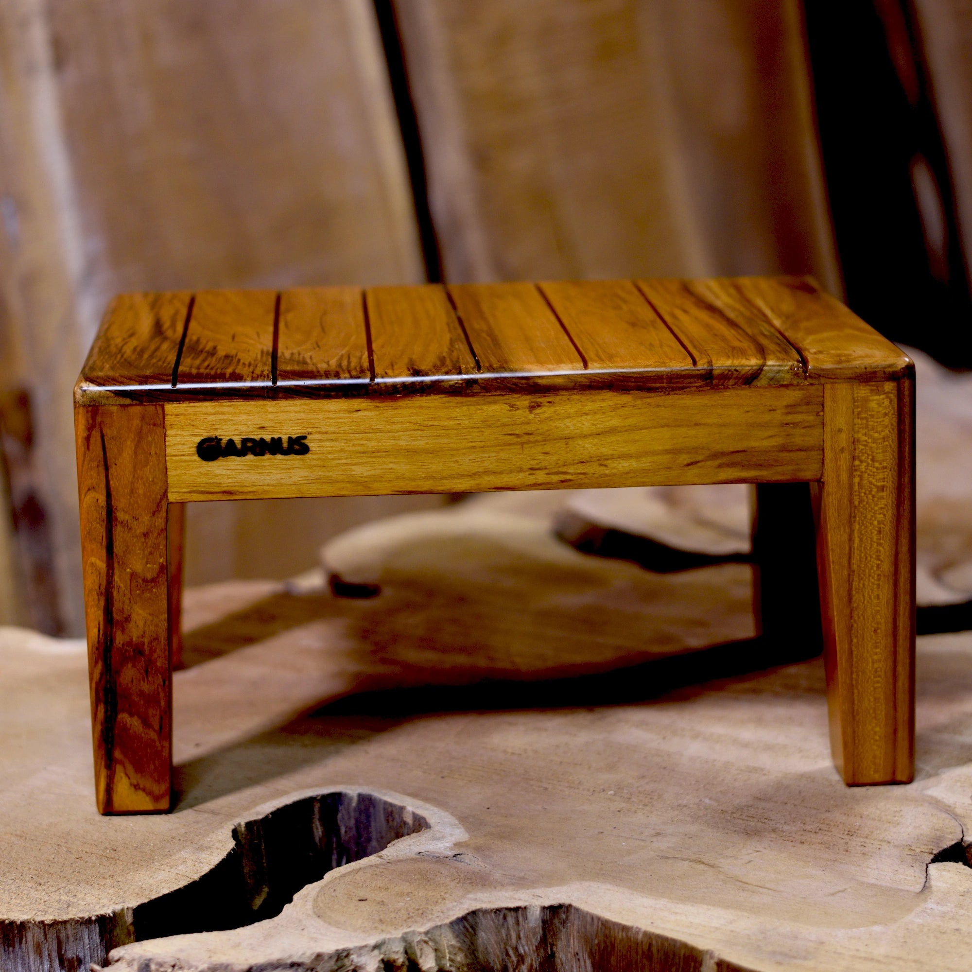 Wooden stool with 'Garnus' branding on a textured surface