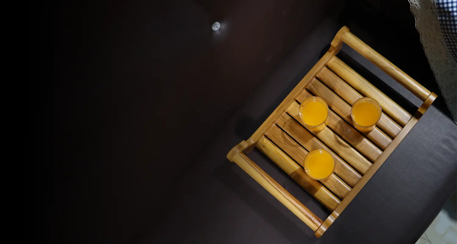 Three glasses of orange juice on a wooden tray with a dark background