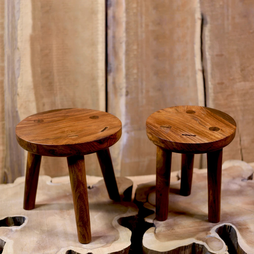 Two wooden stools on a textured surface with a neutral background